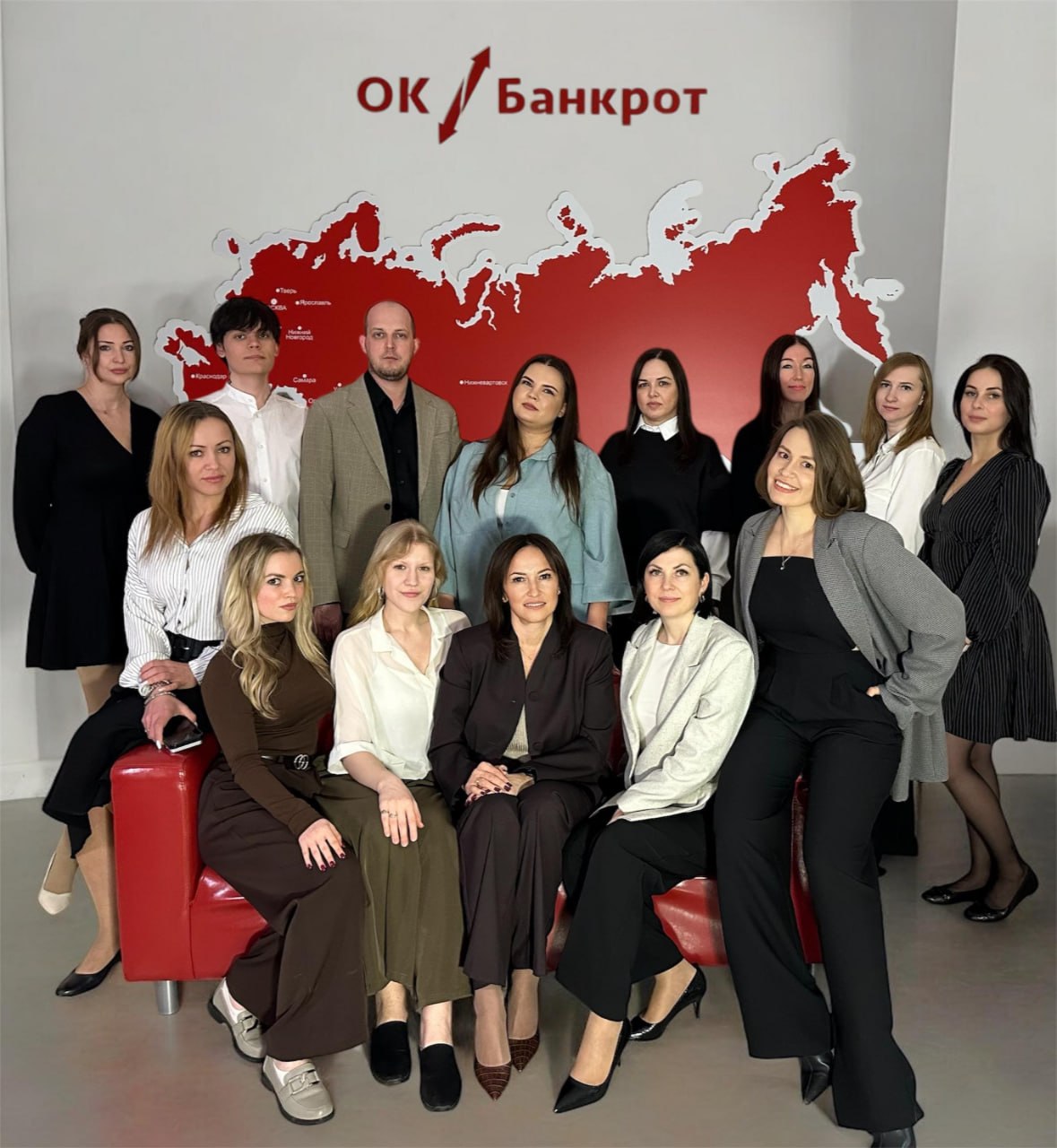 Команда ОК Банкрот в тюменском офисе на фоне логотипа и карты федеральной сети